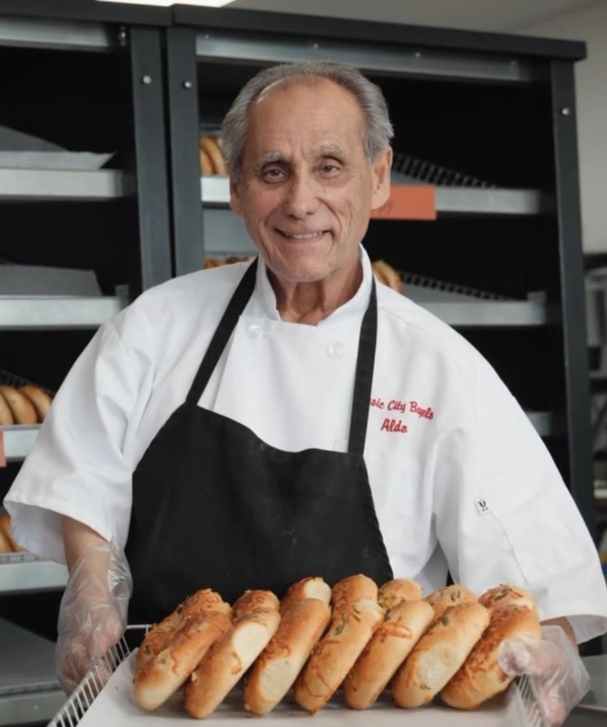 Aldo Stassi holding a tray of fresh baked bagels at Music City Bagels
